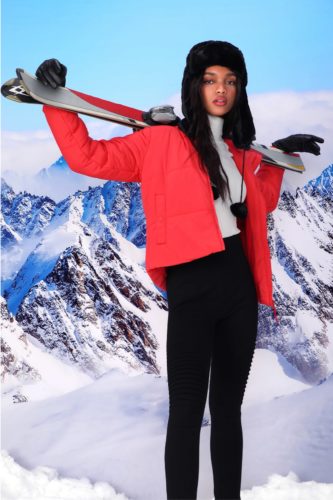 Winter snow outfit with black leggings, cream turtleneck, bright red puffer coat, boots, black hat